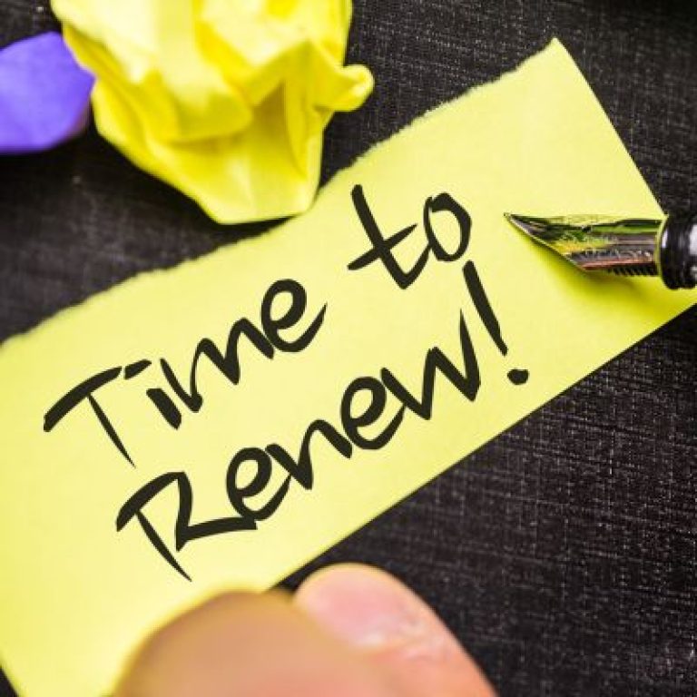 Yellow sticky note with the handwritten words “Time to Renew!” beside a fountain pen and crumpled paper.